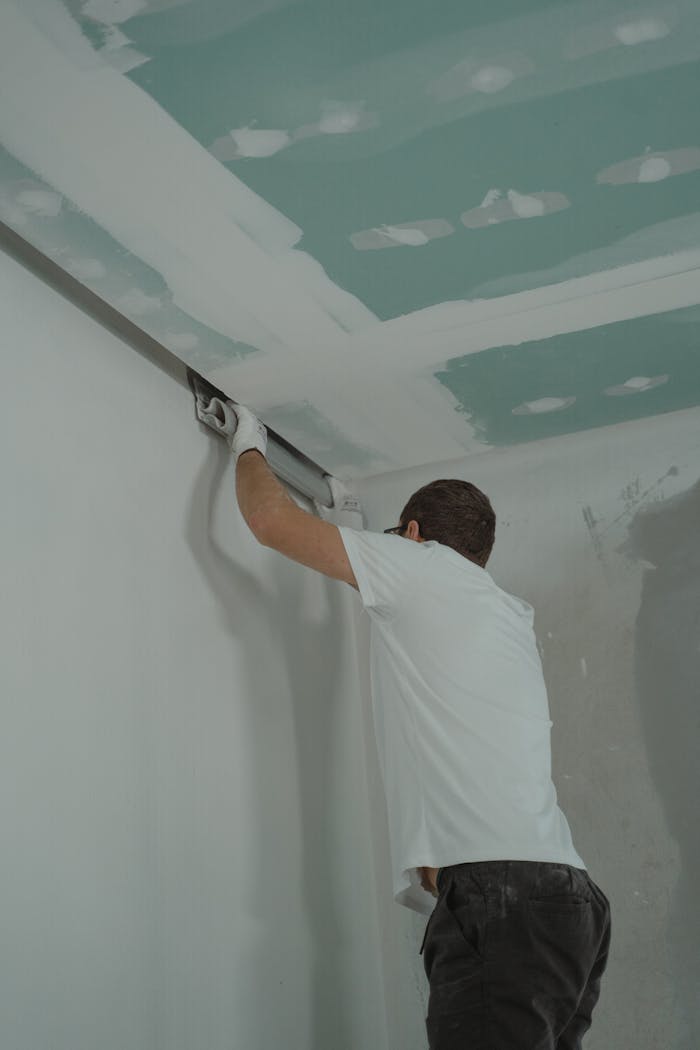 why-choose-us A man works meticulously on drywall installation during a house renovation.
