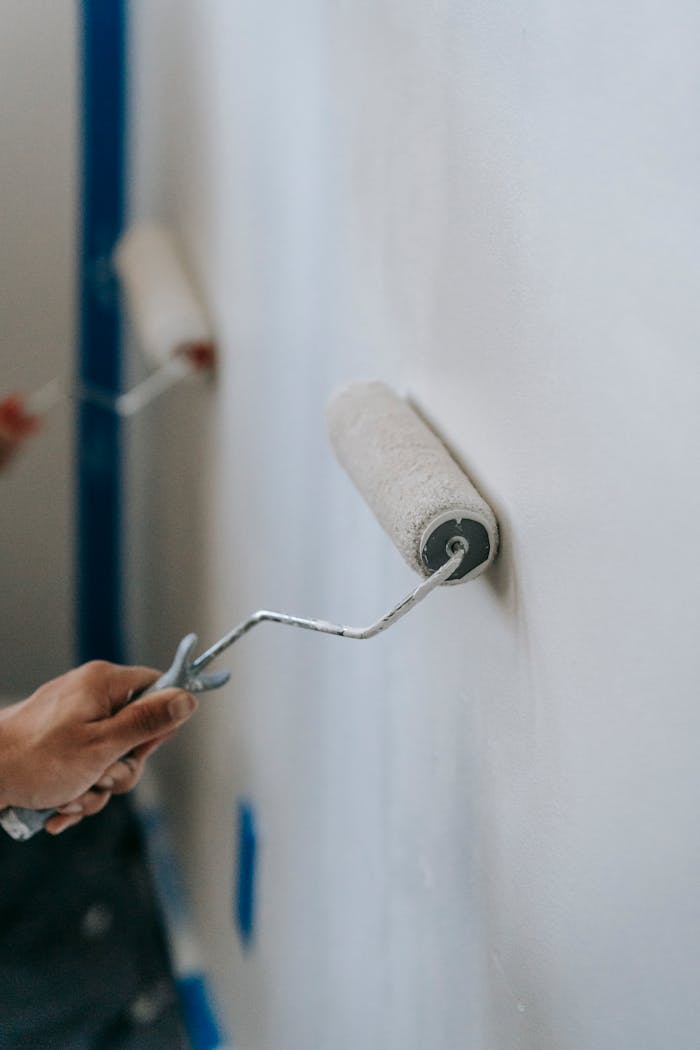 creative Close-up of hands using paint rollers to renovate an interior wall of a home.